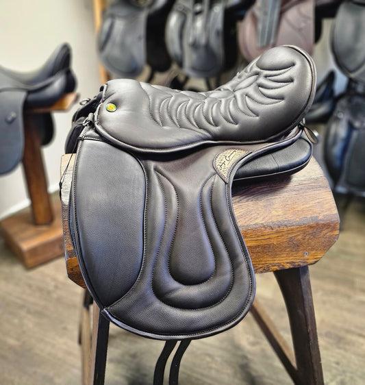 A black Cloud All Purpose softleather saddle positioned on a wooden stool, featuring a slightly forward-flanged saddle flap compared to a dressage saddle, with an A-frame seat and attached stirrup bars.